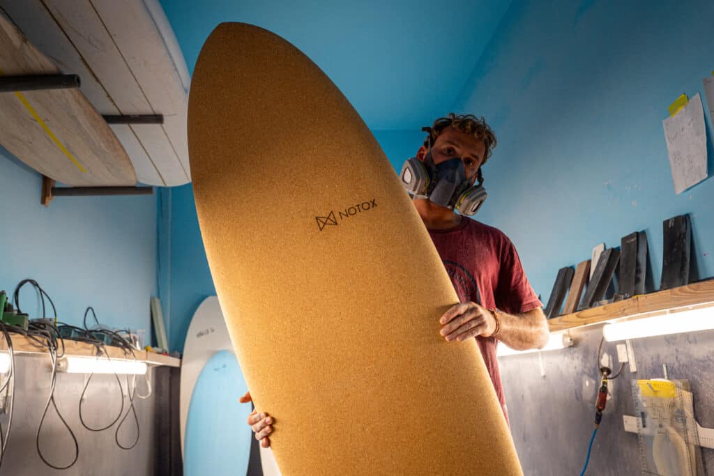 Shaper tenant une planche de surf en liège NOTOX.